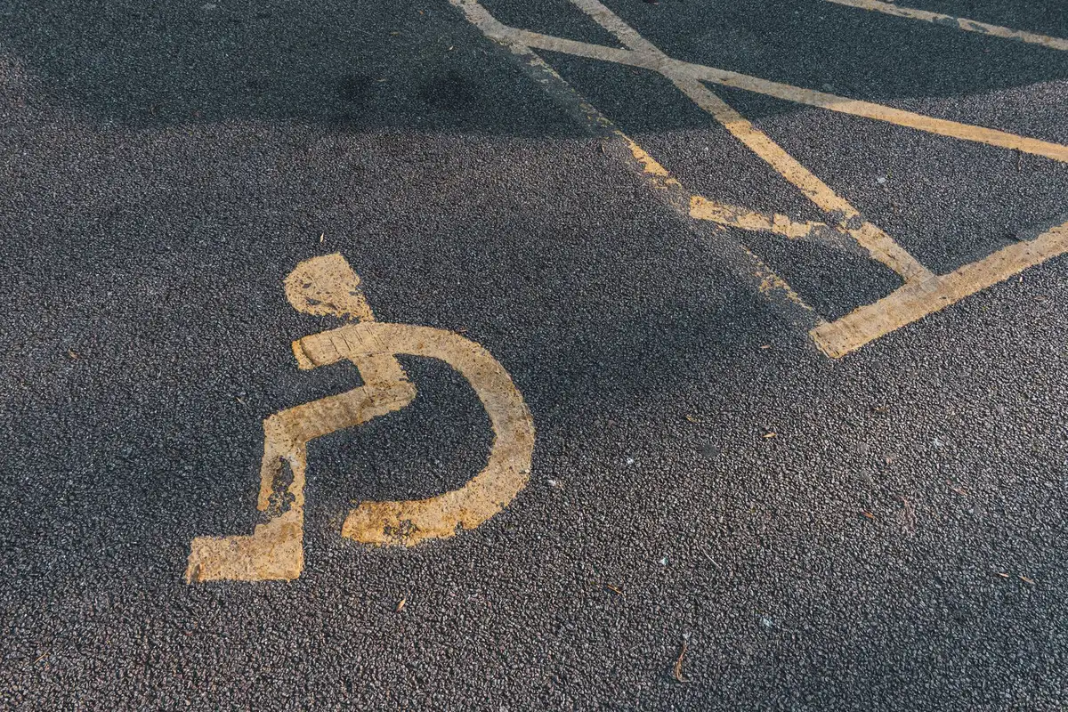 ADA accessible parking symbol stenciled in yellow paint on dark asphalt