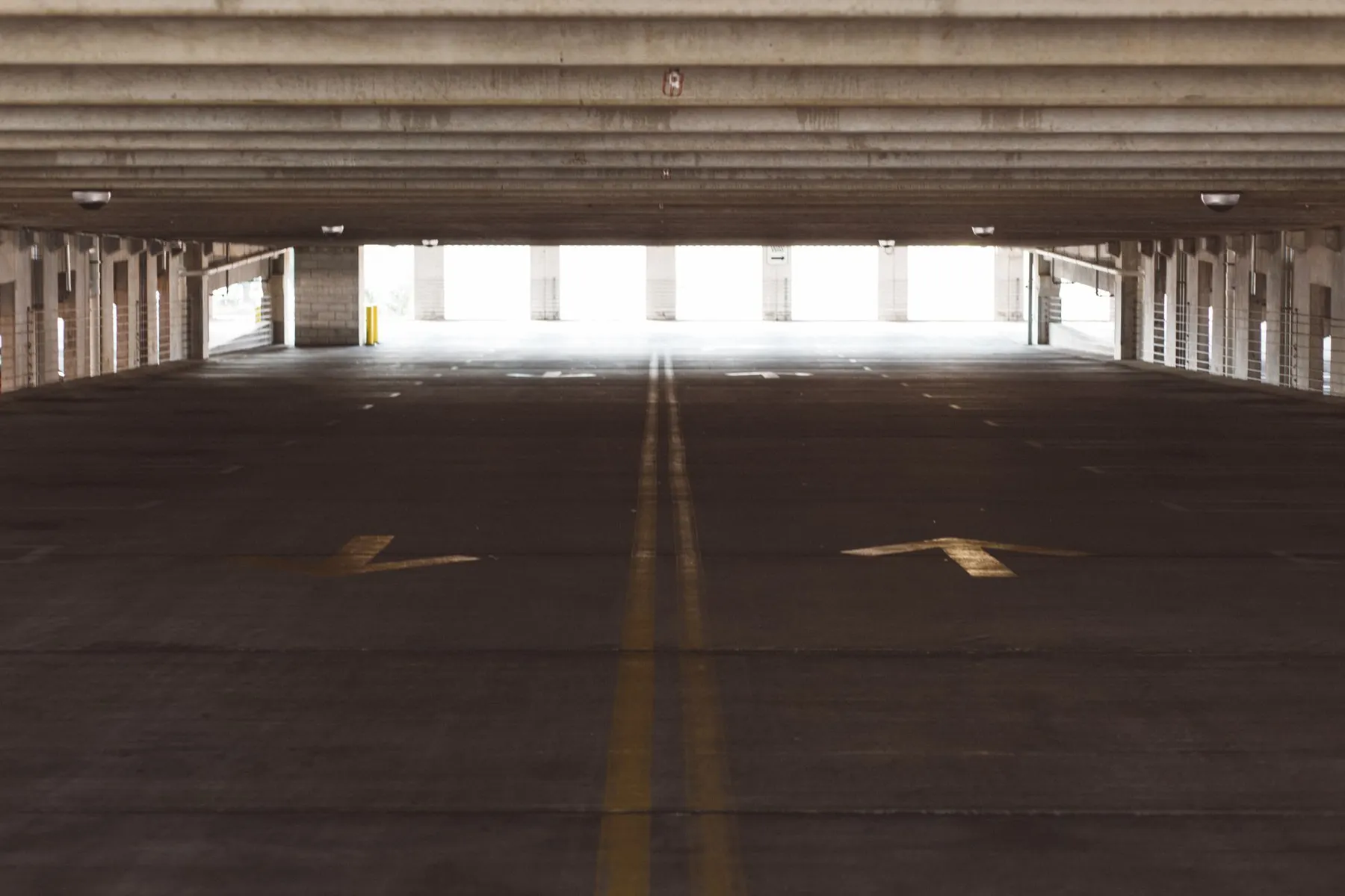 Deep one-point perspective down a parking structure lane with painted directional arrows